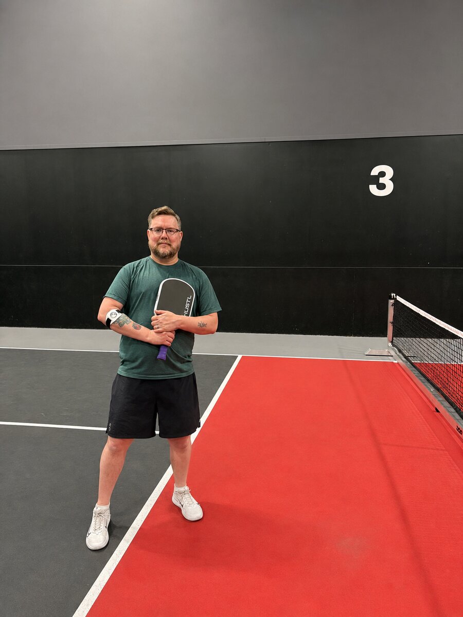 Nick Carter holding a pickleball paddle on an indoor court